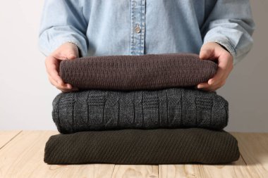 Ahşap masadaki katlanmış süveterli kadın arka planda, yakın plan.