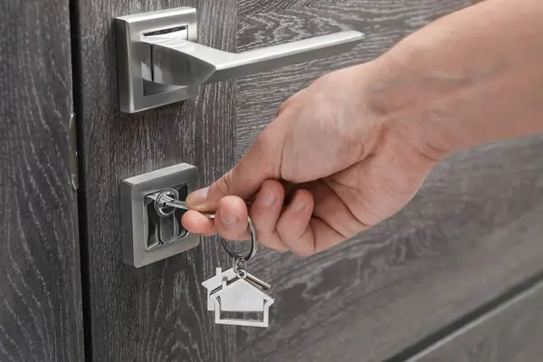 Man unlocking door with key, closeup view