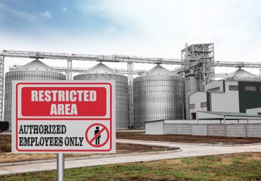 Sign with text Restricted Area Authorized Employees Only near granaries outdoors clipart