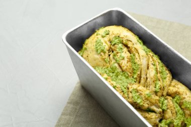 Pişmemiş pesto ekmeği, yemek kabında ışık masasında, metin için yer var.