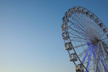 Büyük dönme dolap açık mavi gökyüzüne karşı, alçak açı. Metin için boşluk