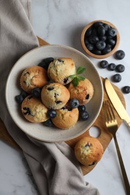 Lezzetli çörekler kasede yaban mersini ve beyaz mermer masa üzerinde çatal bıçak, düz yatıyordu.