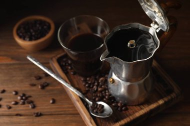 Demlenmiş kahve, moka demliği ve ahşap masada fasulye.