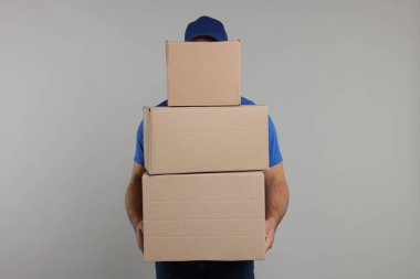 Gri arkaplanda paket yığını olan kurye