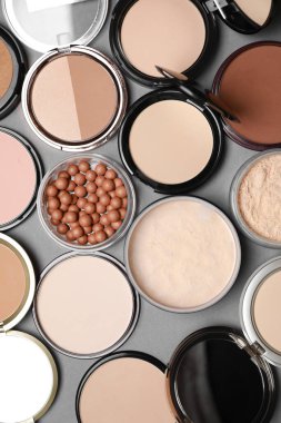 Different face powders on grey background, flat lay clipart