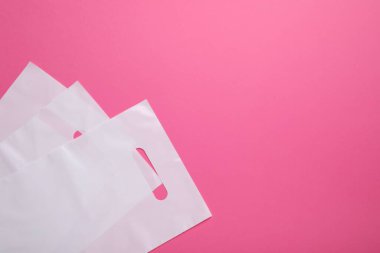 Pembe arka planda beyaz plastik torbalar, üst manzara. Metin için boşluk