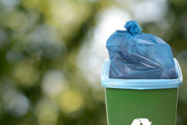 Çöp poşeti dolu çöp tenekesi bulanık arkaplanda, metin için boşluk