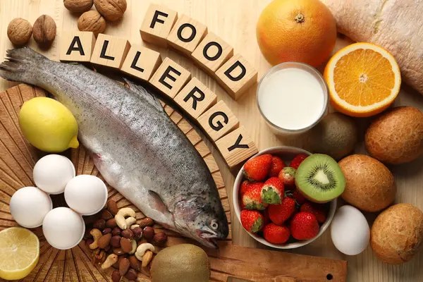 Food allergy. Different fresh products and cubes on wooden table, flat lay