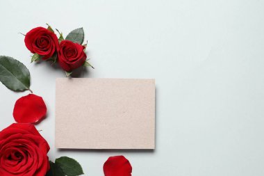 Boş kart, güzel kırmızı güller ve açık arkaplanda yapraklar, düz bir zemin. Metin için boşluk