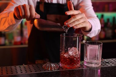 Alkolik kokteyl yapmak. Barmen bardaki bardağa buz küpleri ekliyor, yakın plan.