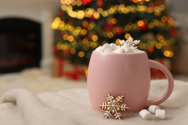 Kapalı mekanda yumuşak battaniyede pembe bardakta şekerlemeli Noel kakaosu, yakın plan. Metin için boşluk