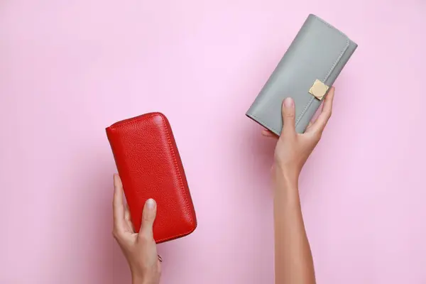 Woman holding leather purses on pink background, closeup