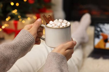 Lezzetli kakao içen ve evde Noel filmi izleyen bir kadın.