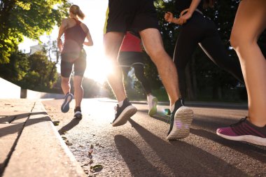 Güneşli bir günde, arka planda koşan bir grup insan.