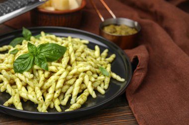 Pesto soslu lezzetli trofie makarna ve ahşap masada fesleğen yaprağı, yakın plan. Metin için boşluk