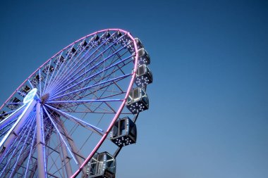 Mavi gökyüzüne karşı büyük parlayan dönme dolap, alçak açı. Metin için boşluk