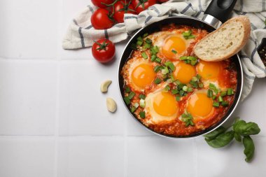 Lezzetli Shakshuka kızartma tavasında beyaz fayanslı masada servis ediliyor. Metin için boşluk