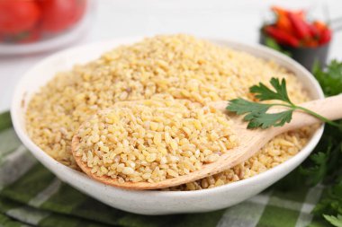 Tabakta çiğ bulgur olan kase ve kaşık, yakın plan.