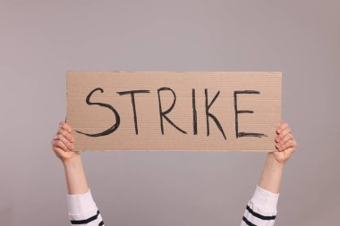 Açık gri arkaplanda kelime grevi yazılı karton pankart tutan kadın, yakın plan