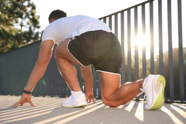 Güneşli bir günde açık havada başlama pozisyonunda koşucu