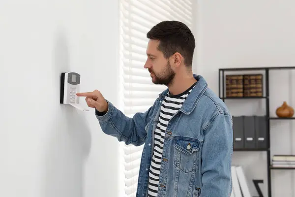 Man entering code on home security system indoors