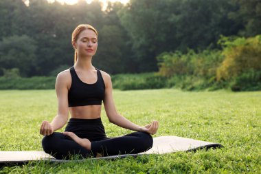 Güzel genç bir kadın yoga minderinde Padmasana egzersizi yapıyor. Lotus pozu