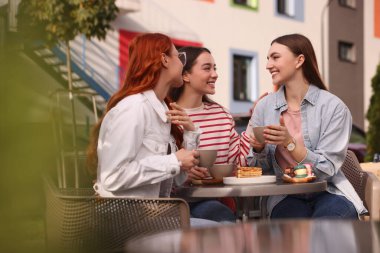 Açık kafede sohbet edip kahve içen mutlu arkadaşlar.