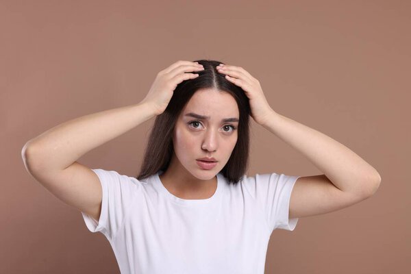 Эмоциональная женщина со здоровыми волосами на бежевом фоне
