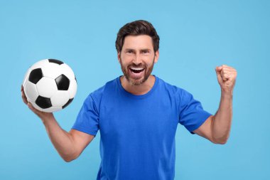 Açık mavi arka planda futbol topuyla duygusal spor hayranı