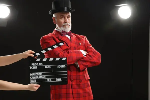 Senior actor performing role while second assistant camera holding clapperboard on stage. Film industry