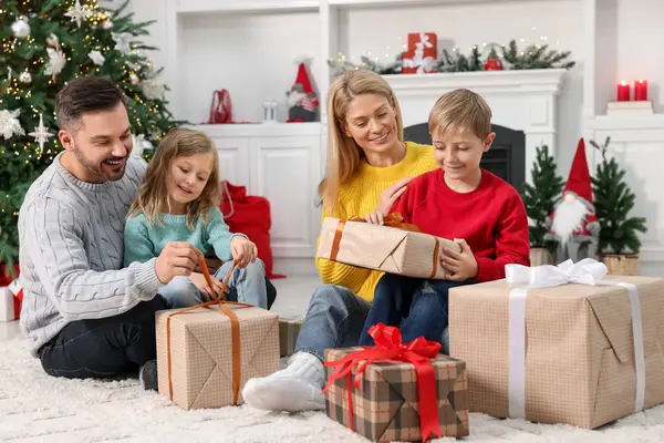 Parents and their children opening Christmas gifts at home