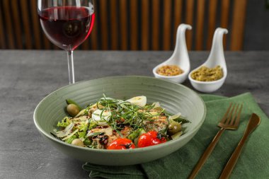 Tarhun soslu lezzetli yemekler, salata sosu ve gri masada servis edilen bir bardak şarap.