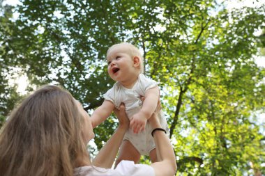 Anne ve tatlı bebeği dışarıda vakit geçiriyorlar, düşük açılı bir manzara. Metin için boşluk