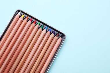 Açık mavi zemin üzerinde renkli pastel kalemler, üst görünümde metin için boşluk. Malzemeler çiziliyor