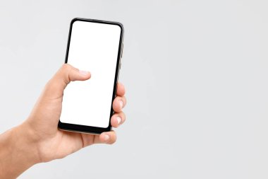 Açık gri arka planda boş ekranlı akıllı telefon tutan adam, yakın plan. Tasarım için model