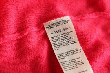 Pembe giysi üzerinde farklı dillerde kıyafet etiketi, yakın plan