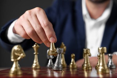 Man with game piece playing chess at checkerboard against dark background, closeup clipart