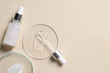 Bir şişe kozmetik serumu ve bej arka planda örnekler içeren petri kapları. Metin için boşluk