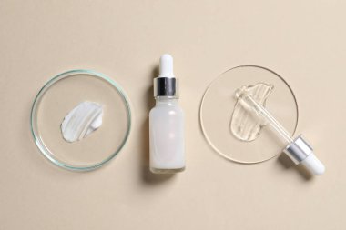 Bir şişe kozmetik serumu ve bej arka planda örnekler içeren petri kapları.