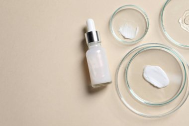 Bir şişe kozmetik serumu ve bej arka planda örnekler içeren petri kapları. Metin için boşluk