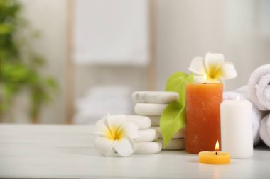Beyaz masa üzerinde farklı spa ürünleri ve plumeria çiçekleri içeren kompozisyon, metin için boşluk