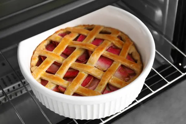 Baking dish with tasty apple pie in open oven, closeup