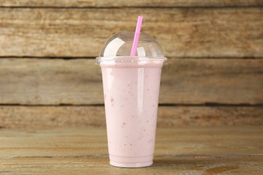 Ahşap masada plastik bir bardak lezzetli meyve püresi