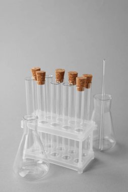 Test tüpleri ve bej arka planda farklı laboratuvar şişeleri.