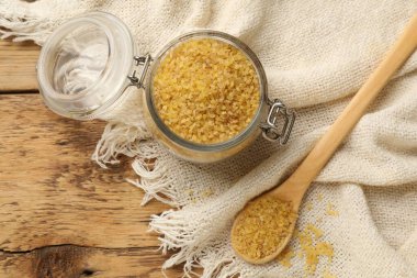 Cam kavanoz ve kaşık çiğ bulgur ile ahşap masa, düz yatıyordu