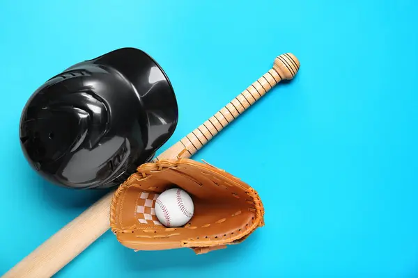 Baseball glove, bat, ball and batting helmet on light blue background, flat lay