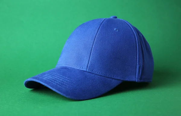 Stylish blue baseball cap on green background