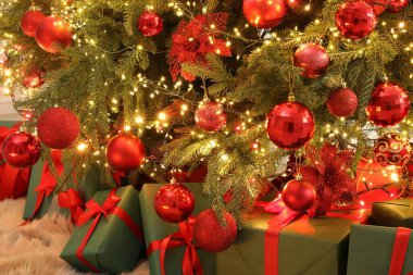 Kapalı alandaki Noel ağacının altında birçok hediye kutusu var.