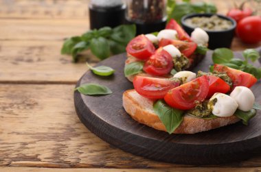 Nefis Caprese sandviçleri, mozzarella, domates, fesleğen ve pesto sosu ahşap masada, yakın plan. Metin için boşluk