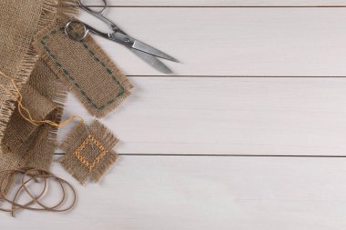 Beyaz ahşap masa üzerinde çuval bezi parçaları ile düz kompozisyon, metin için boşluk